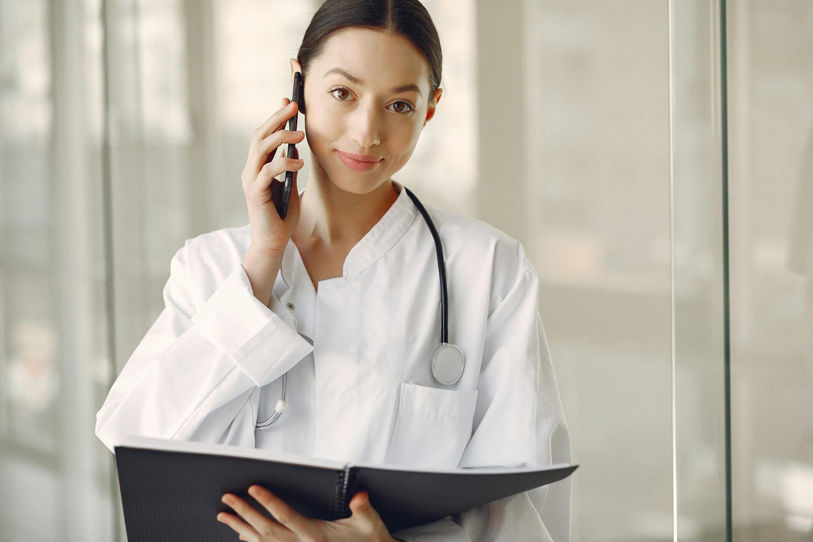 Professional female doctor in white coat talking on phone in medical clinic.